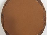 a round mirror with a wooden frame on top of a white pedestal