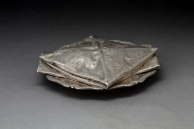 une assiette en argent sur laquelle est posée une serviette pliée