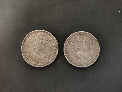 two silver coins on a black surface