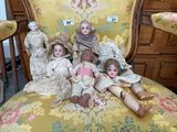 five dolls sitting on a chair in a room