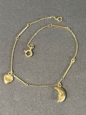 a gold bracelet with a crescent charm and a heart charm