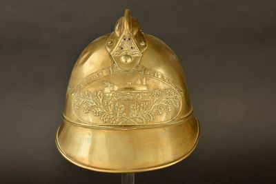 casque plaqué or posé sur un socle, sur fond noir, avec un fond noir