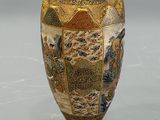 a gold vase with a picture of people on it