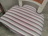 a chair that has a cushion on it in front of a chair