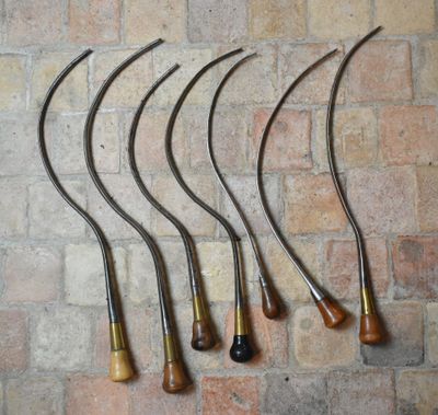 six pipes à fumer antiques alignées contre un mur de briques