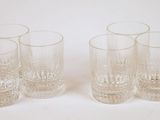 four glasses are lined up in a row on a white surface