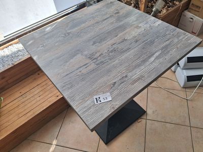 a wooden table with a metal base on a tiled floor