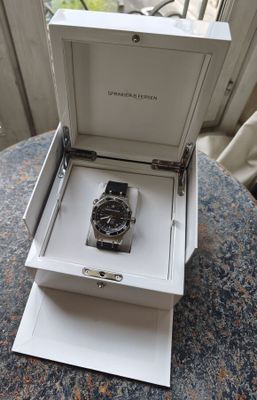 a watch in a box on a table by a window
