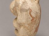 un vieux vase orné d'un visage sur un fond gris