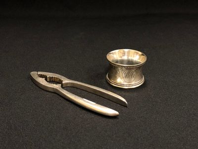 une coupe en argent et une pince posées sur une table noire