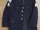 navy blue military jacket with patches and buttons on a wooden floor