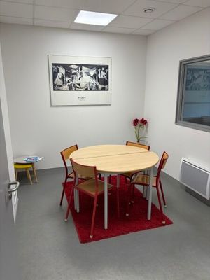 une table et des chaises dans une pièce où il y a un tableau accroché au mur