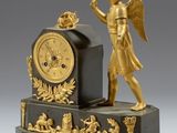 une statue en or représentant un ange avec une horloge, posée sur un socle