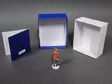 a small figurine of a man standing in front of a box