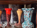 many vases and glasses on a shelf in a room