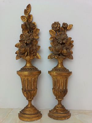 two gold vases with flowers on them sitting on a table