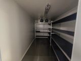 an image of a narrow room with shelves and a fan