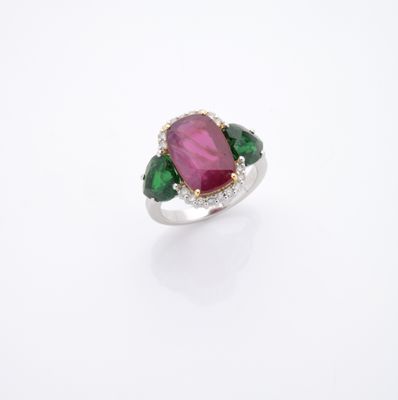 un gros plan d'une bague rose et verte posée sur une surface blanche