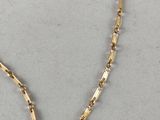 a close up of a gold chain necklace on a white surface