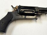 un vieux revolver posé sur une surface blanche, avec une crosse noire