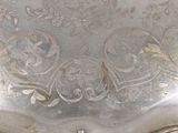 an antique silver plate with a floral design on it