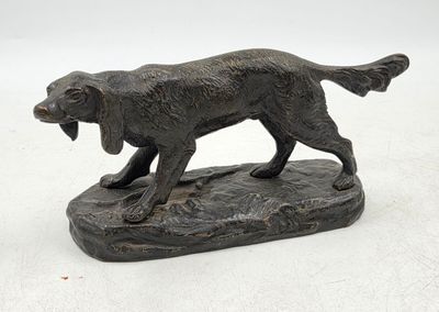 statue d'un chien tenant un os dans la gueule, posé sur un rocher