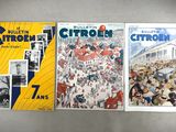 three books are lined up on a table in front of a gray wall