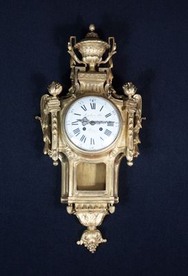 une horloge dorée accrochée au mur, sur fond noir