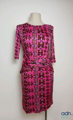 a pink dress on a mannequin stand against a white wall