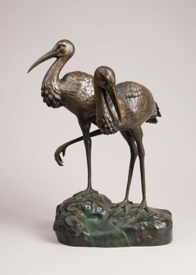 bronze statue of two birds standing on a rock on a white background