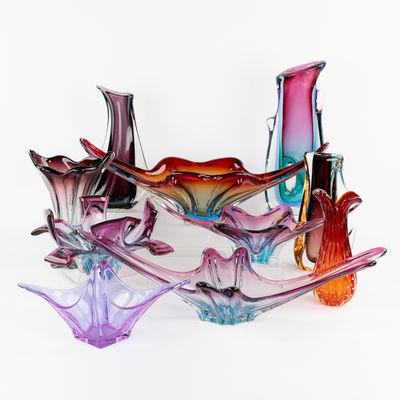 de nombreux vases en verre de différentes couleurs posés sur une surface blanche