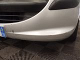 the front bumper of a white car with a blue tag on it