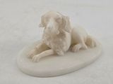 statue of a dog on a surfboard on a white surface