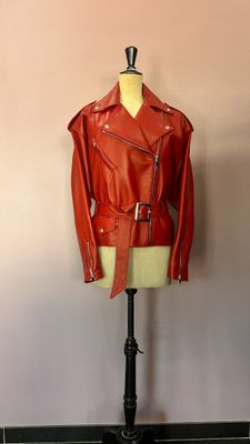 une veste en cuir rouge posée sur un mannequin devant un mur rose