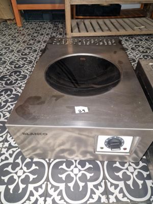 une cuisinière argentée posée sur un sol carrelé dans une cuisine