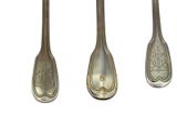 three silver spoons are lined up on a white surface