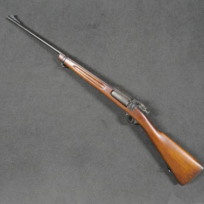 a rifle with a wooden barrel and a wooden handle on a gray surface