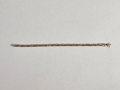 un gros plan d'une chaîne posée sur une surface blanche, avec un morceau de papier en arrière-plan