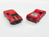 two red toy cars sitting next to each other on a white surface
