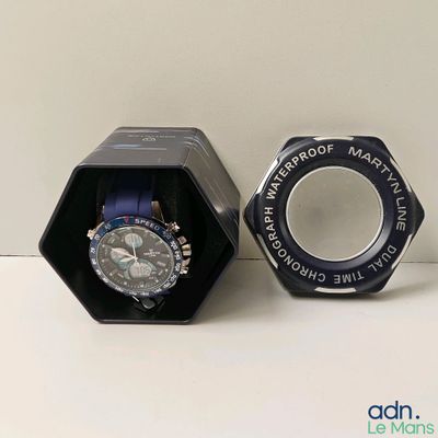 une montre dans une boîte noire posée sur une table blanche