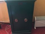 un coffre-fort vert posé par terre à côté d'un radiateur