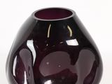 un vase violet posé sur une surface blanche