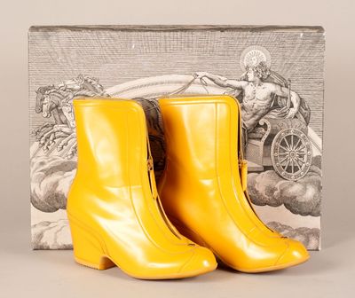 des bottines en cuir jaune avec une boîte de livres en arrière-plan