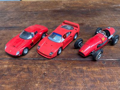 Trois petites voitures rouges sont alignées sur une table en bois