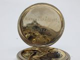 a gold pocket watch sitting on top of a white table