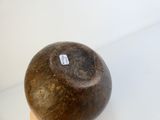 une boule de noix de coco posée sur un support en bois, sur une surface blanche