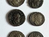 six ancient roman coins are shown in a row on a white surface