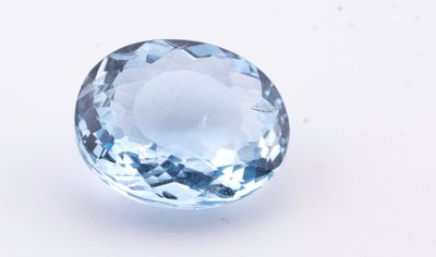 un gros plan d'une topaze bleue posée sur une surface blanche