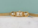 an antique ladies ' s watch with a gold mesh bracelet