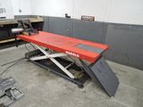 une photo représentant une paire de ciseaux rouges posée sur une table dans un garage